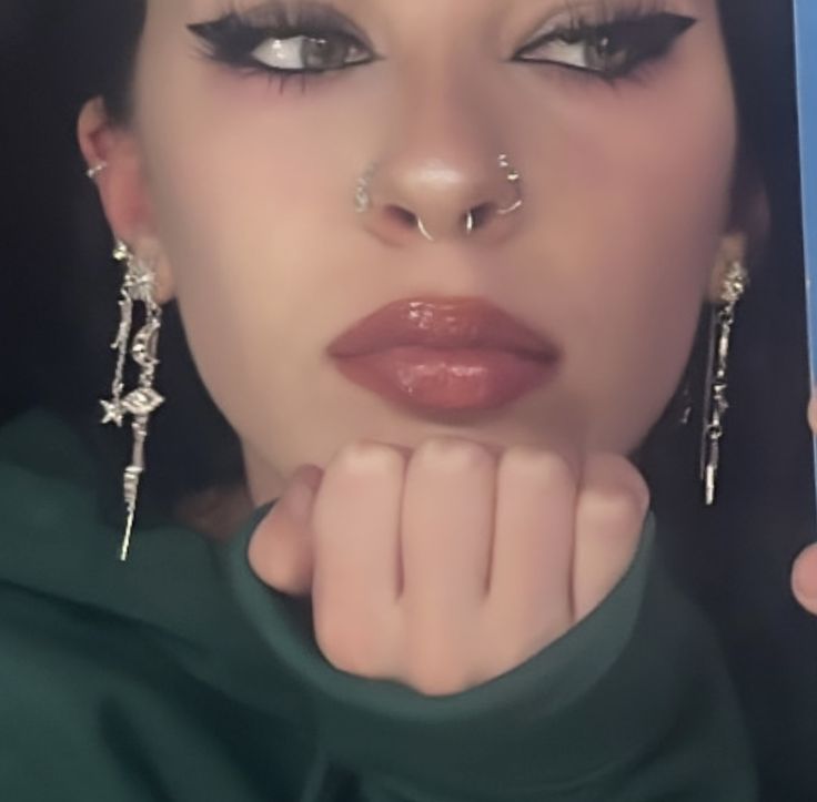 a woman with piercings on her nose is posing for the camera while wearing green