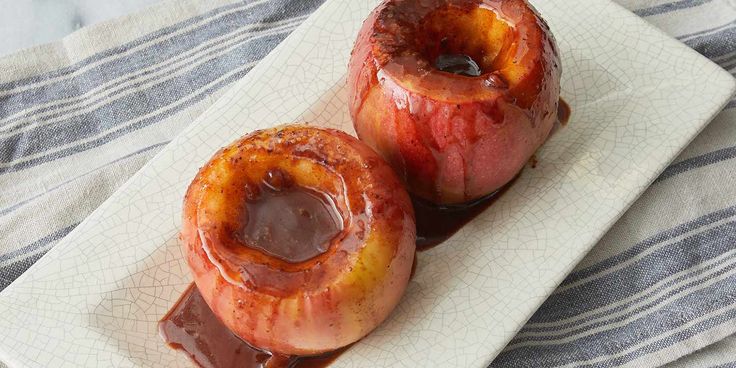 two glazed apples sitting on top of a white plate covered in chocolate and caramel