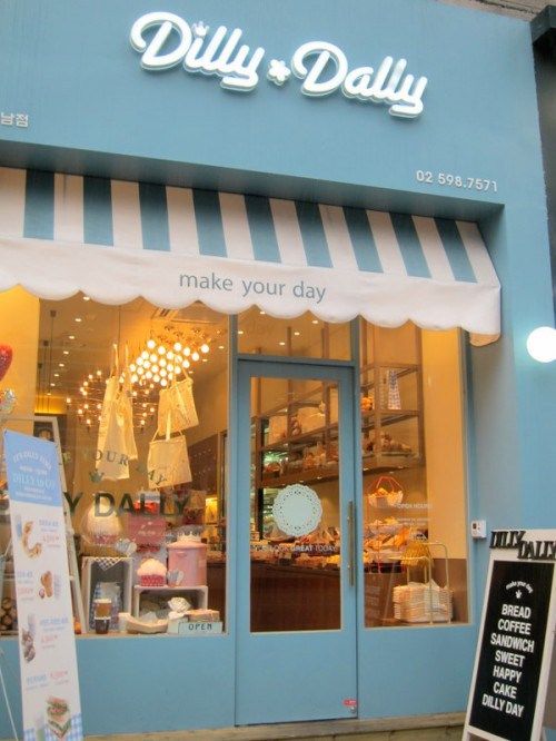 the front of a store with blue doors and white awnings on it's windows