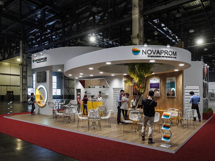 people are standing in front of a booth with chairs and tables on display at an exhibition