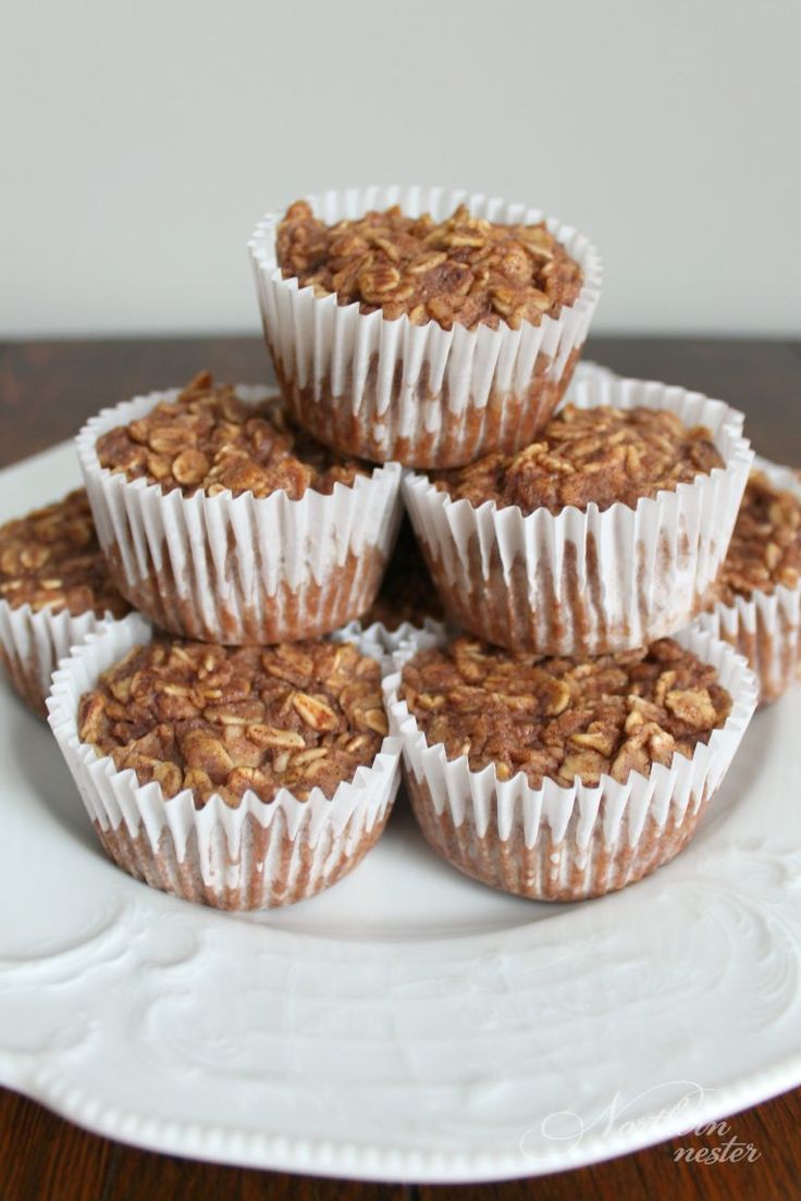 several muffins on a white plate stacked high in the air and topped with oatmeal