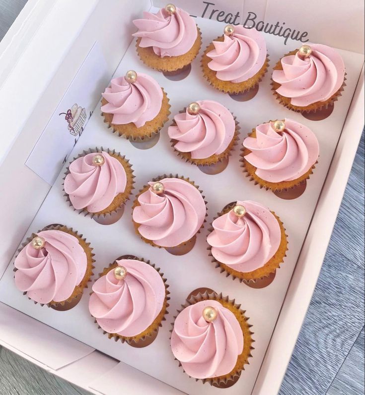 twelve pink frosted cupcakes in a white box