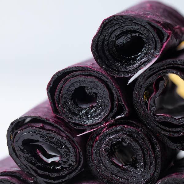 a pile of rolled up purple cloths on top of each other in front of a white background