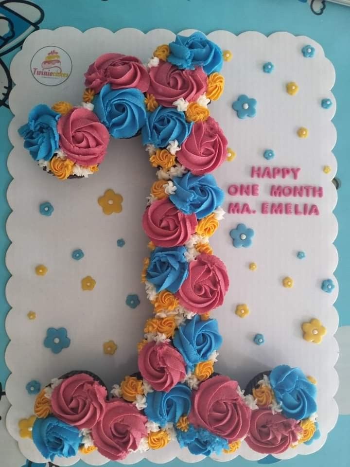 a birthday cake with the number one made out of frosting and flowers on it