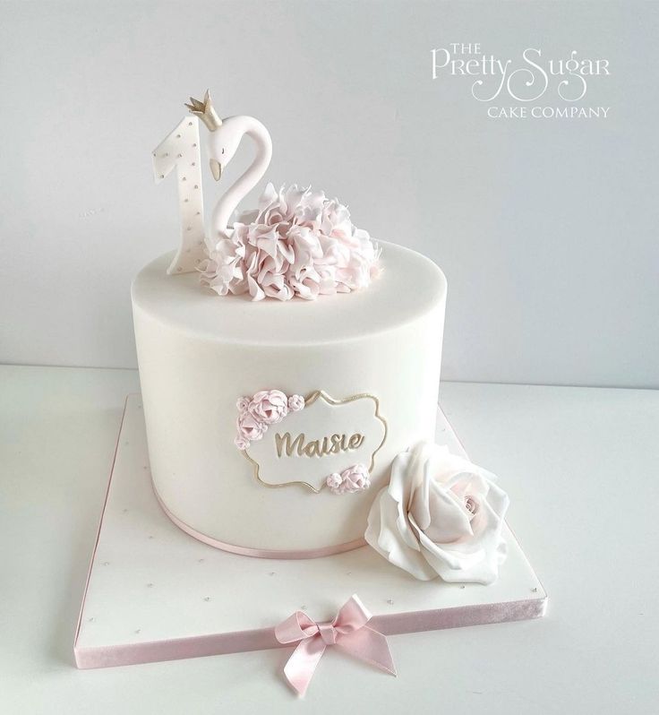 a white cake with pink flowers and a swan on top