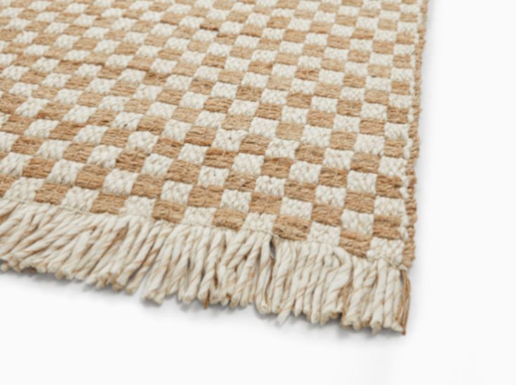 a brown and white checkered rug with fringes on the bottom, sitting on a white surface