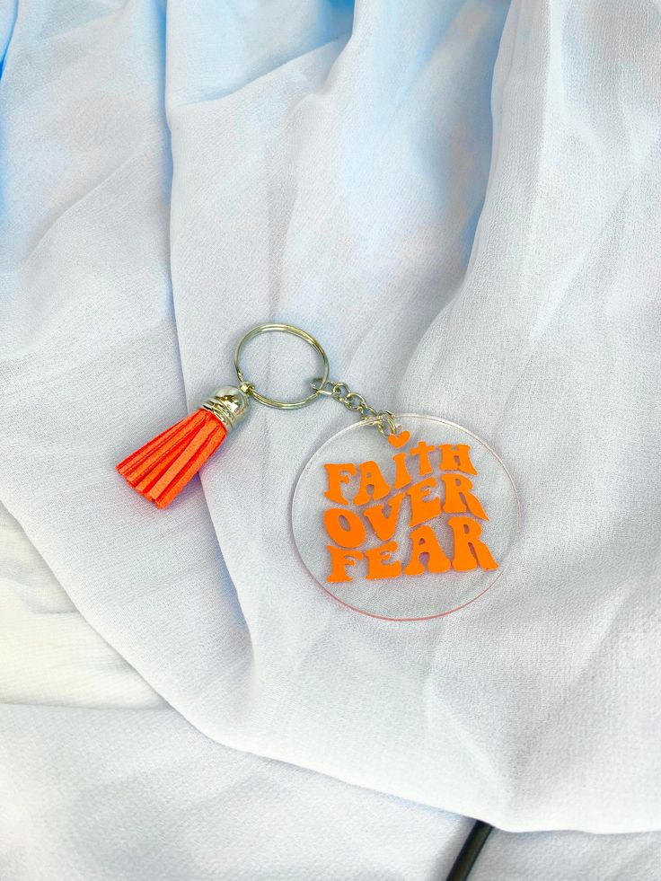 an orange tasseled keychain with the words faith over fear on it