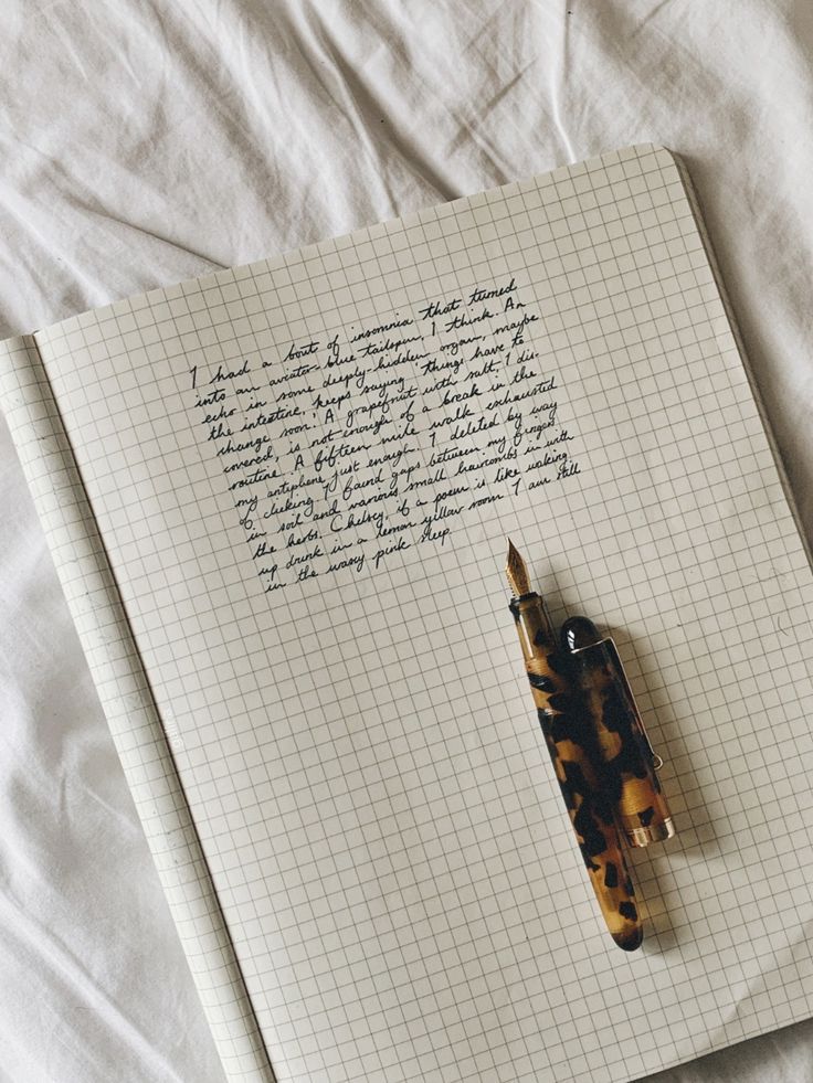 an open notebook with writing on it and a pen stuck in the paper next to it