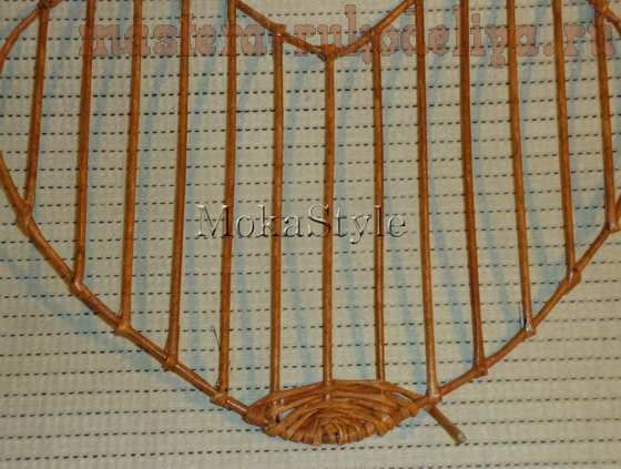 a heart shaped object made out of wood sticks and wire on top of a sheet of paper