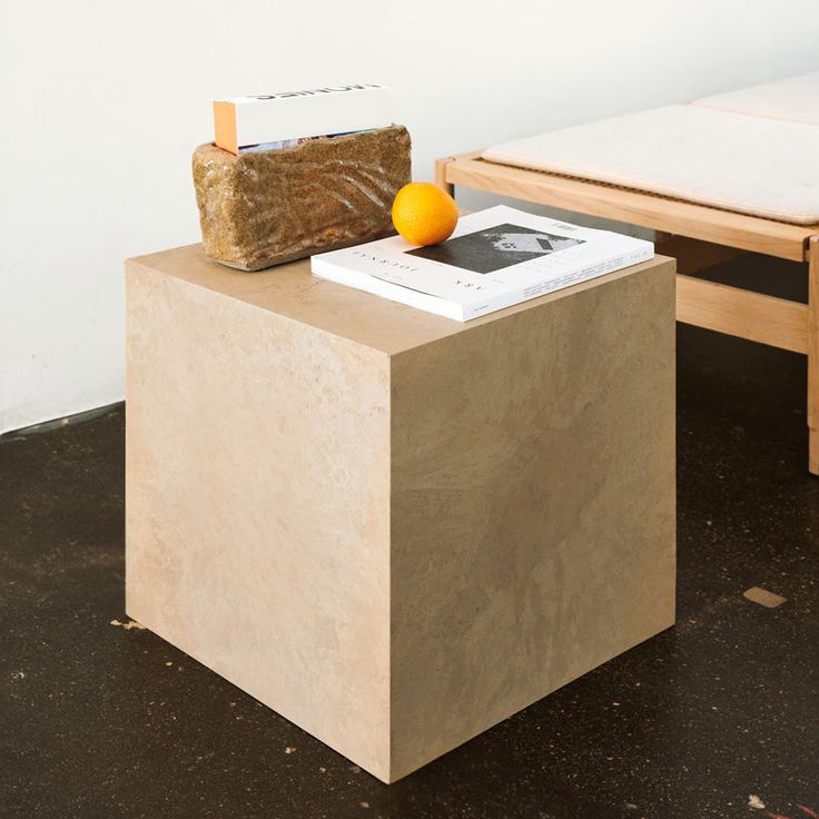 an orange sitting on top of a wooden block next to a table with a bench in the background