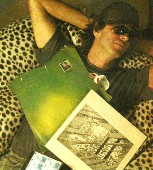 a man laying on top of a leopard print couch next to two books and a cell phone