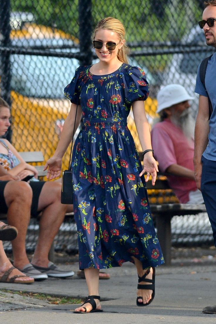 a woman in a blue dress is walking down the street while holding hands with a man