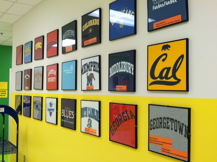 a yellow wall with many framed college sports posters on it, along with a green chair