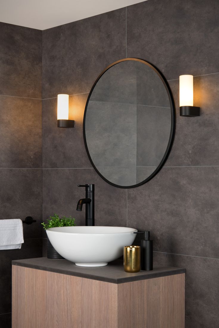 a bathroom with a round mirror above the sink