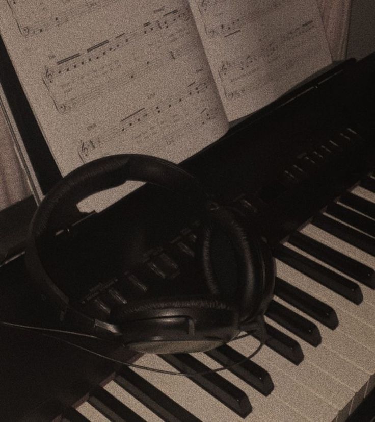 a piano with headphones on top of it and sheet music in the back ground