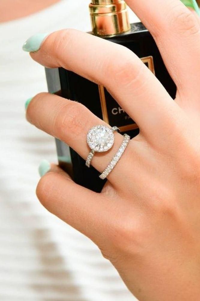 a woman is holding her engagement ring and perfume bottle