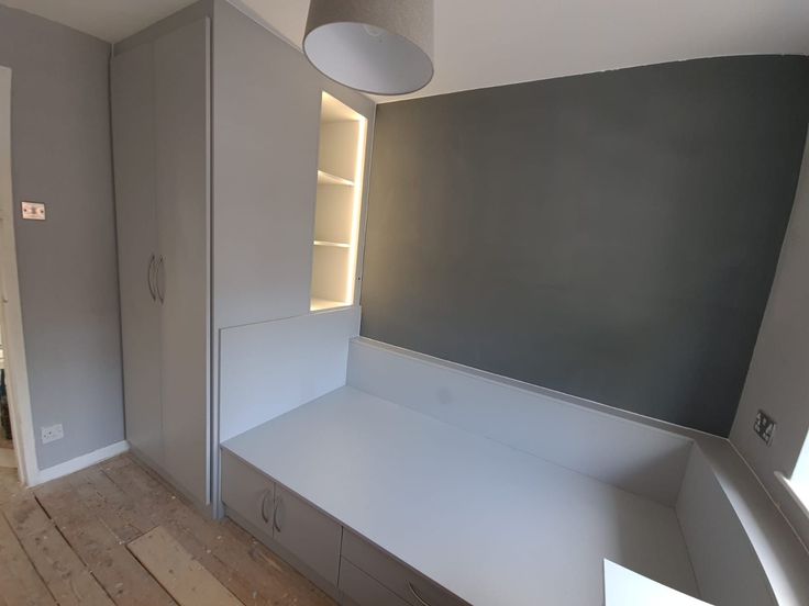 an empty room with white furniture and gray walls, along with wooden flooring in the foreground