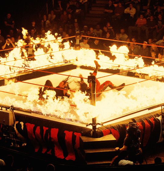 a wrestling match with flames in the ring