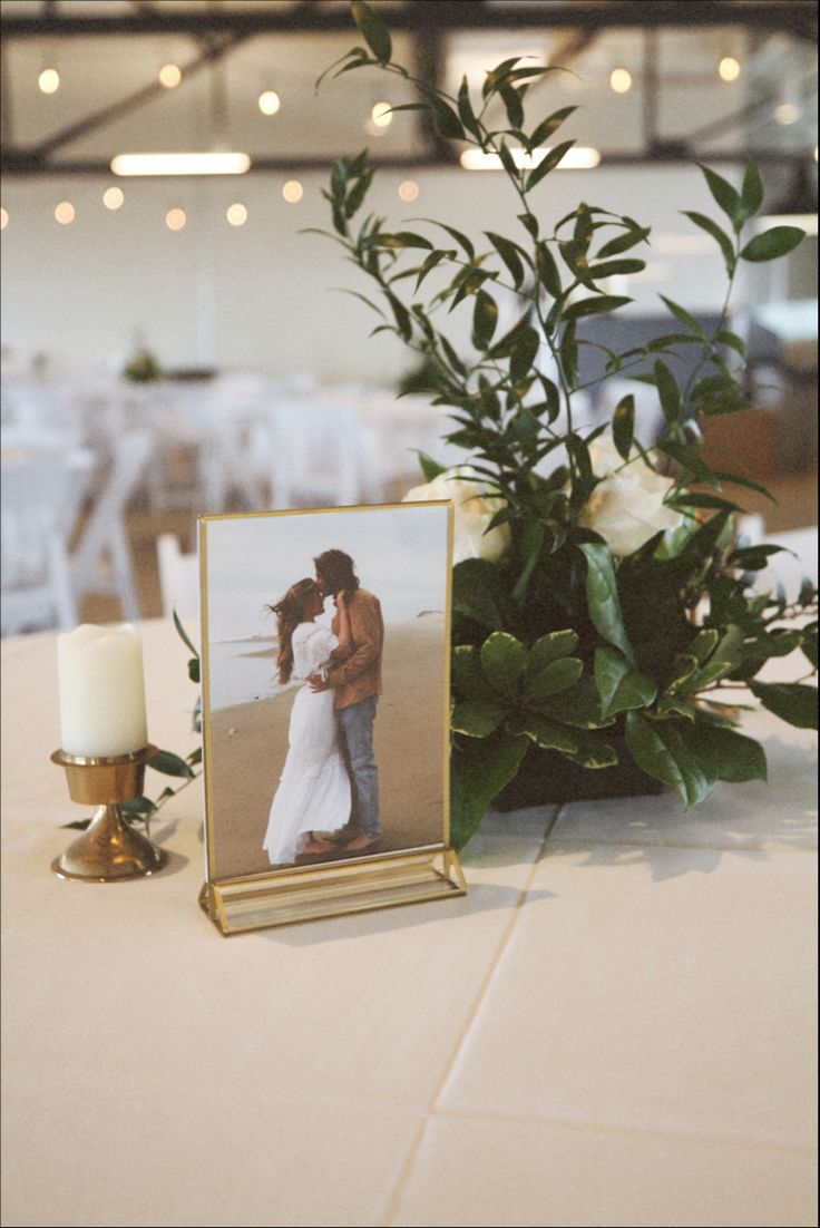 a photo frame sitting on top of a table next to a vase filled with flowers