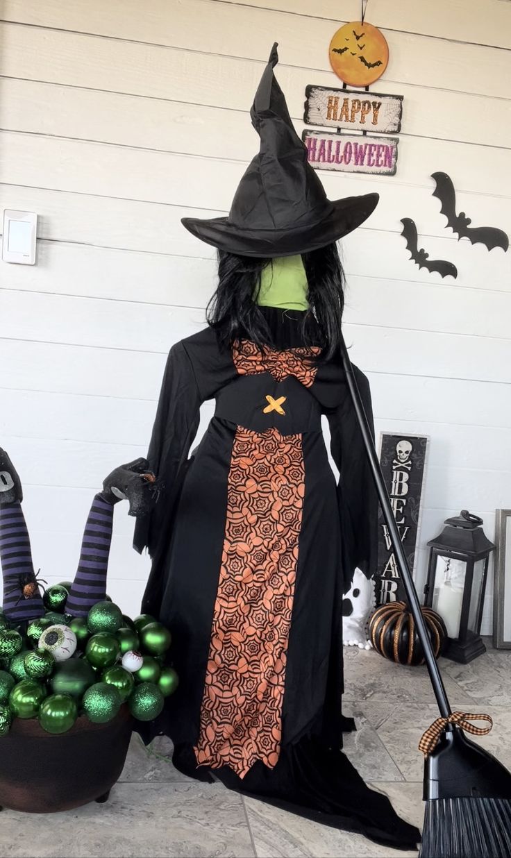 a couple of witches sitting next to each other in front of a house with halloween decorations