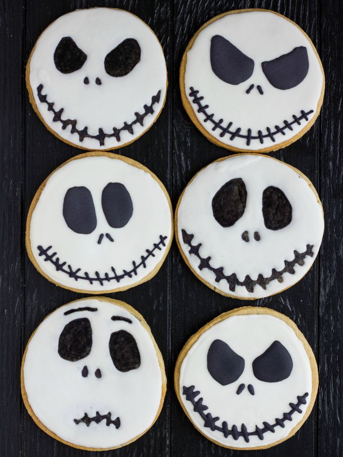 halloween cookies decorated with icing and faces on top of a wooden table next to an orange pumpkin