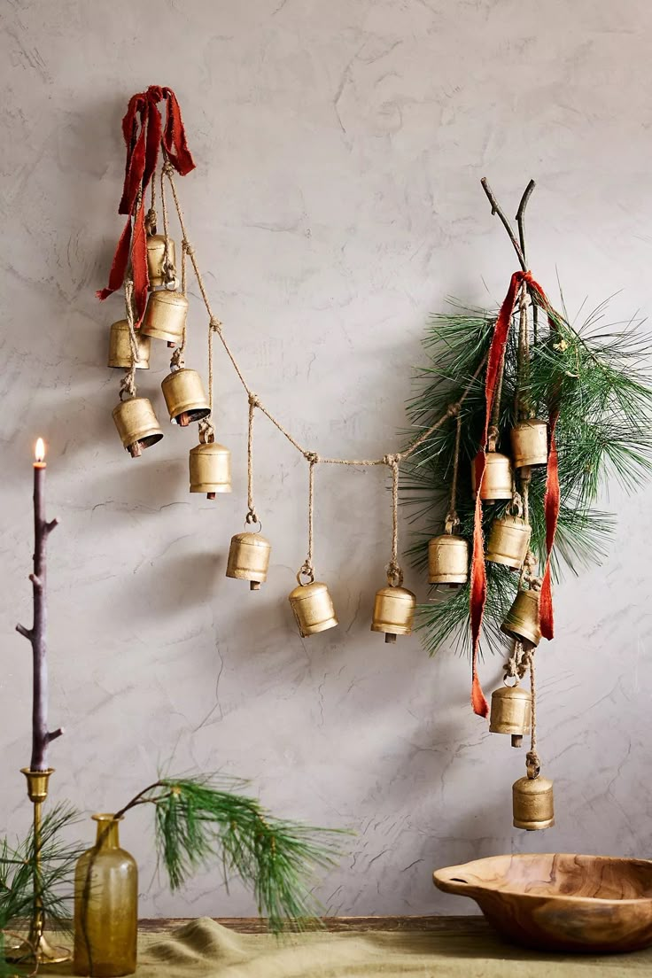 christmas decorations with bells and pine branches hanging from the wall