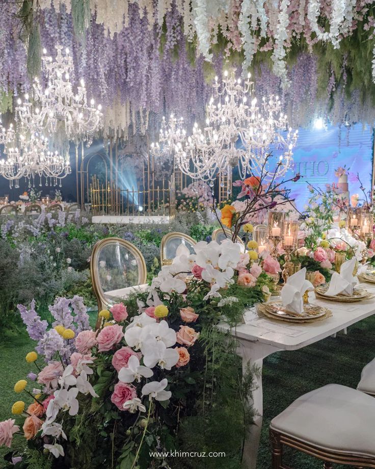 a table set up with flowers and candles for a formal dinner or function in the garden