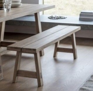 a wooden bench sitting on top of a hard wood floor next to a large window