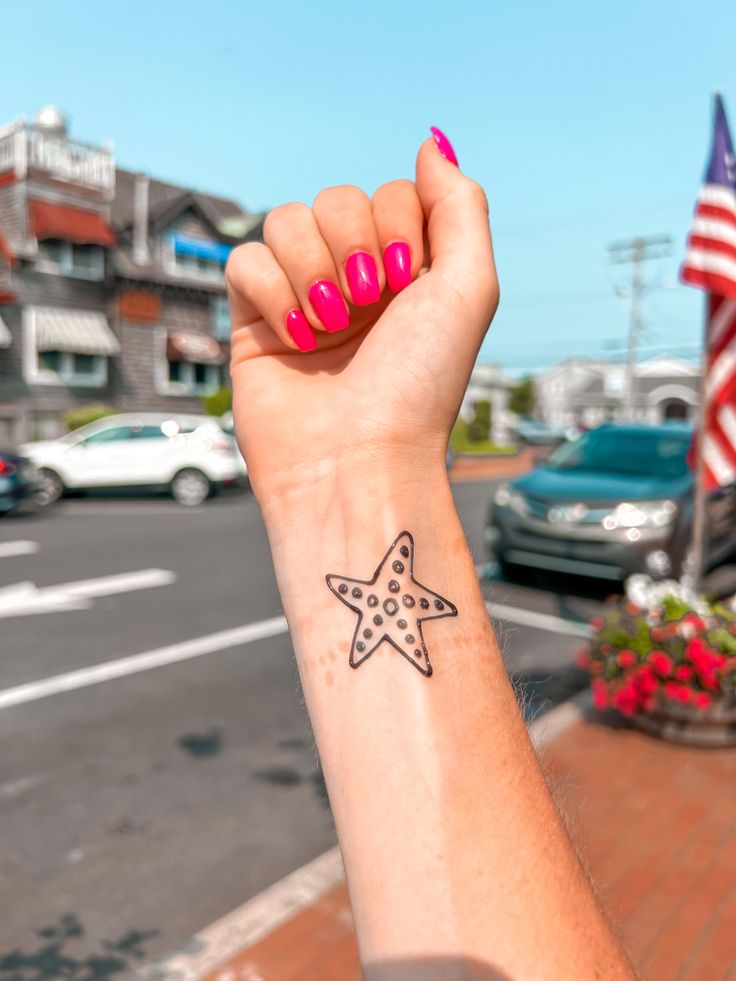 a woman's arm with a small star tattoo on the left side of her wrist