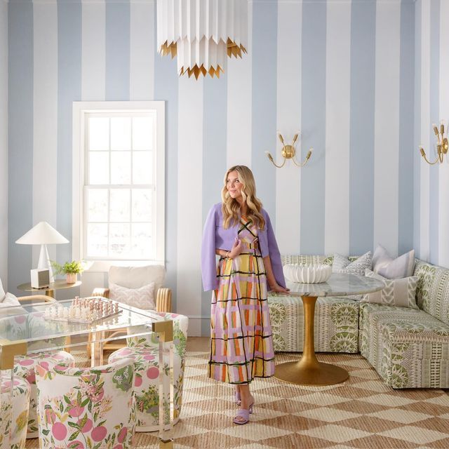 a woman standing in the middle of a living room with blue and white striped walls