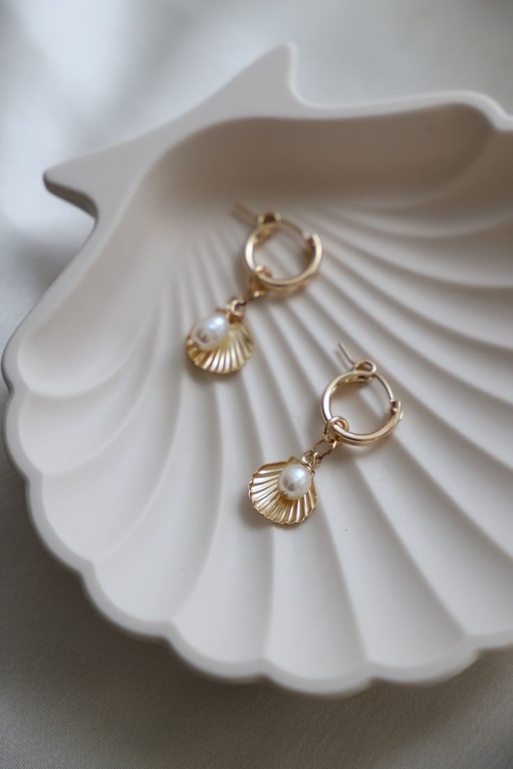 Featuring gold filled hoops adorned with a freshwater pearl and a charming gold filled shell dangle, these earrings will add a touch of seaside style to any outfit. Perfect for beach babes Material: Gold filled, freshwater pearls Size: 13mm hoop, 11mm shell dangle, organic shape rice pearl (size may vary) Shell-shaped Pearl Earrings With Pearl Charm, Pearl Shell Earrings With Pearl Charm, Ocean-inspired Pearl Drop Earrings, Gold Shell Pearl Dangle Earrings, Gold Dangle Shell Earrings With Pearl Drop, Gold Dangle Pearl Earrings With Shell, Gold Shell Pearl Drop Earrings, Gold Dangle Shell Earrings Ocean-inspired, Gold Pearl Drop Earrings With Shell