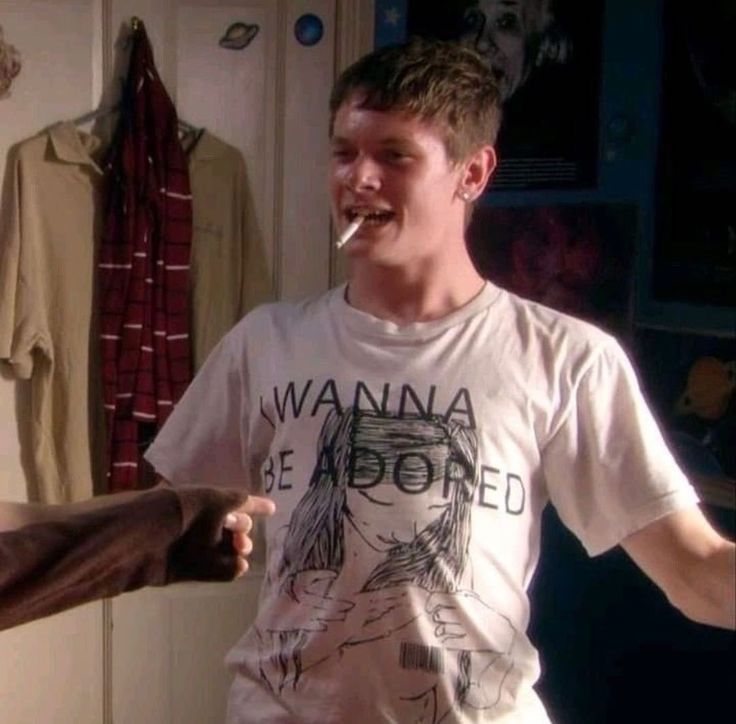 two young men standing next to each other in front of a closet with clothes hanging on the wall