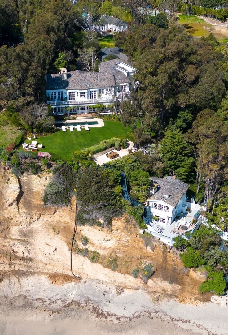 an aerial view of a large house surrounded by trees and sand dunes in the ocean