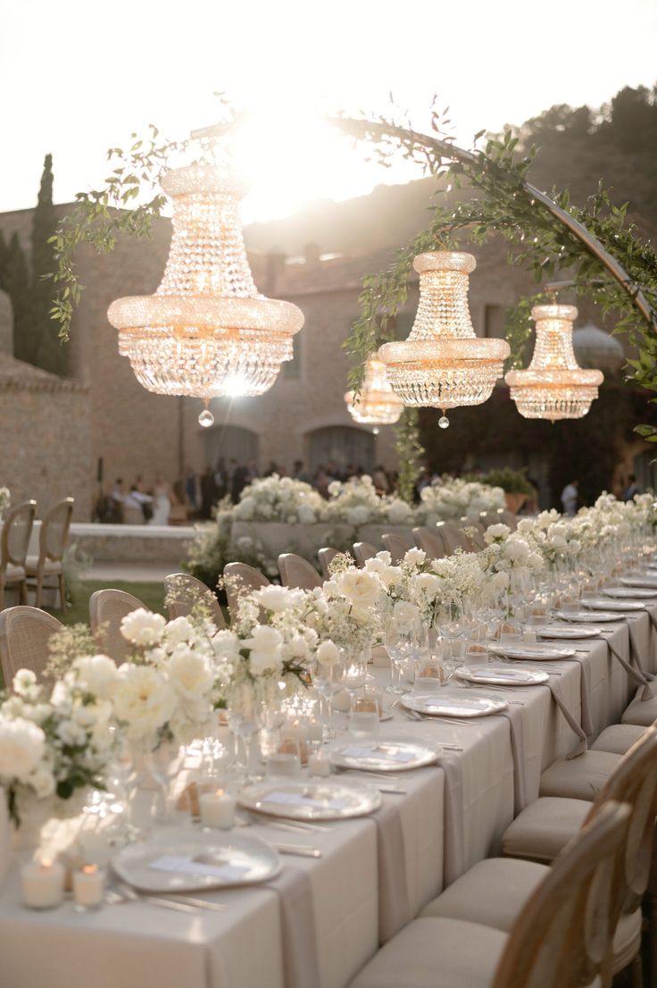 a long table with white flowers and chandeliers