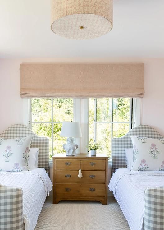 two twin beds sitting next to each other in a room with pink walls and windows