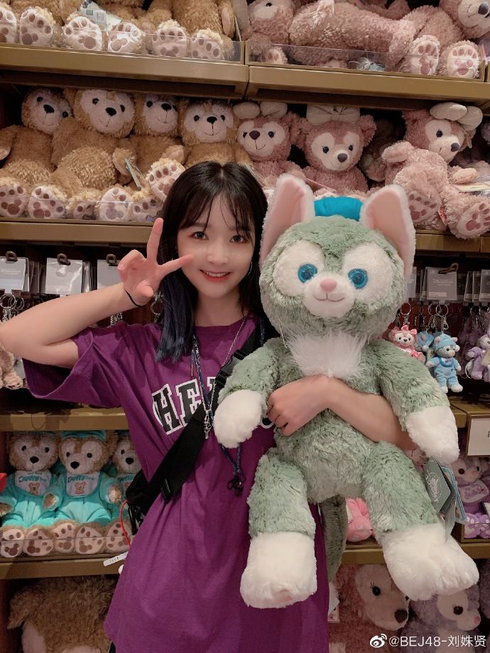 a woman holding a stuffed animal in front of shelves