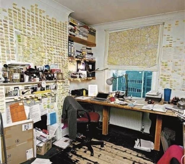 a messy office with lots of clutter on the desk and shelves full of papers