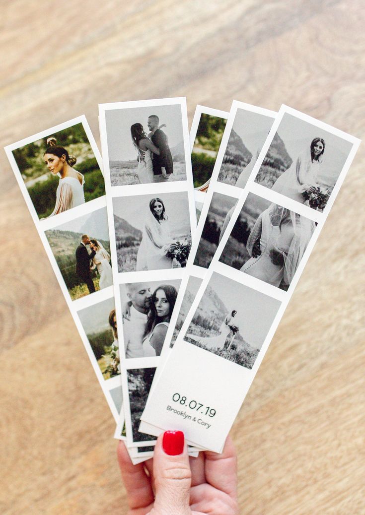 a person holding up several polaroid photos on top of a wooden table in front of them