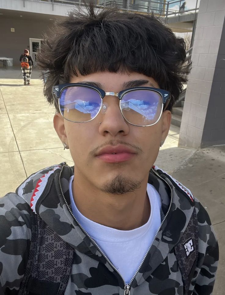 a young man wearing sunglasses and looking at the camera