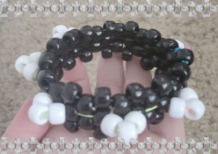 two hands holding black and white beaded bracelets