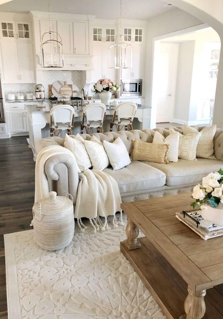 a living room filled with lots of furniture next to a white kitchen and dining area