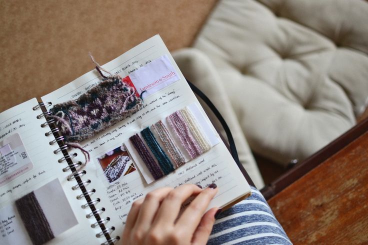 a person is holding a book open to show the contents of their knitting project, including yarns and crochet hooks