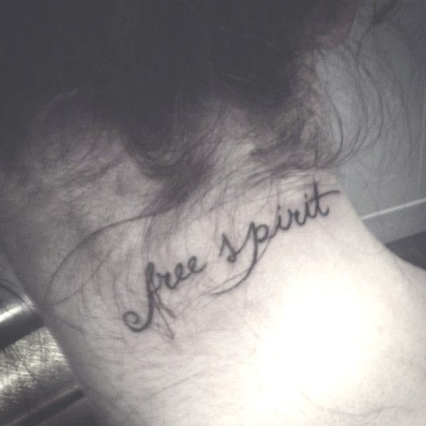 a woman's neck with the word free spirit tattooed on her left side ribcage