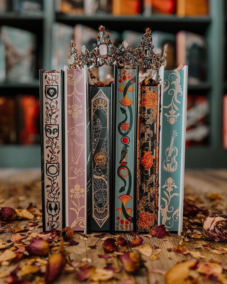 four books are lined up on the floor in front of a bookcase with many books