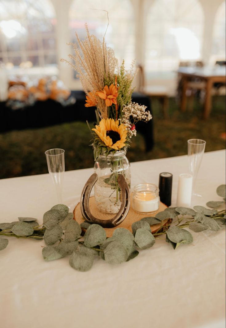 a vase with flowers and greenery on a table in a tented area at an event