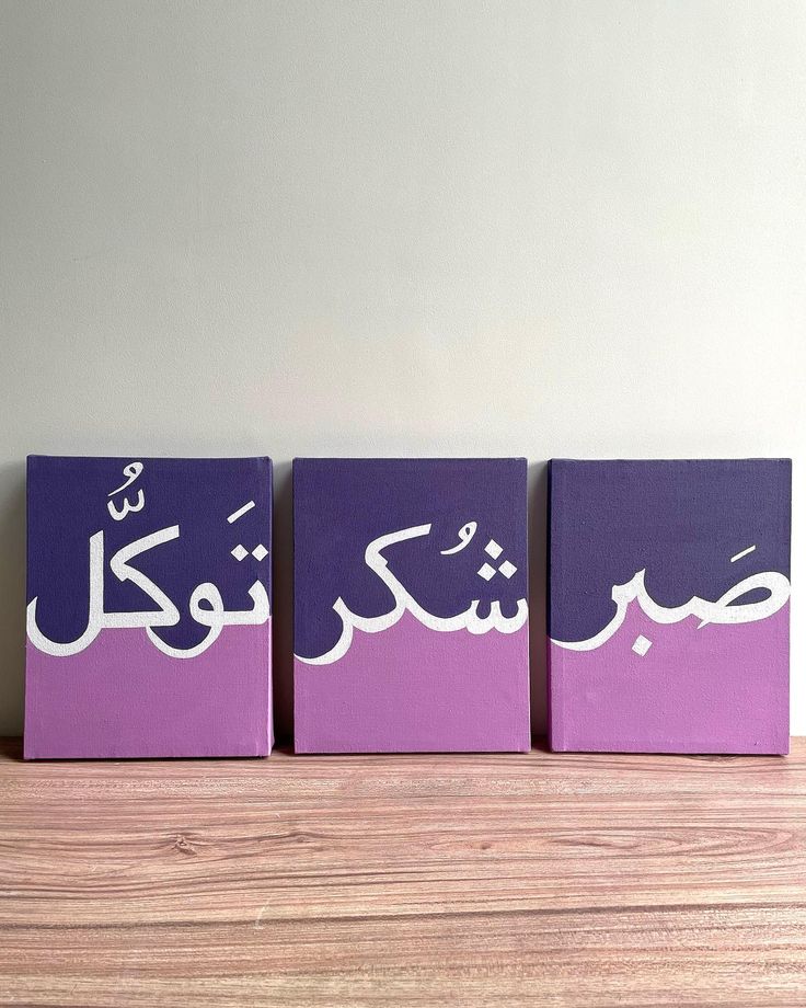 three purple boxes with white writing on them sitting on a wooden table in front of a wall