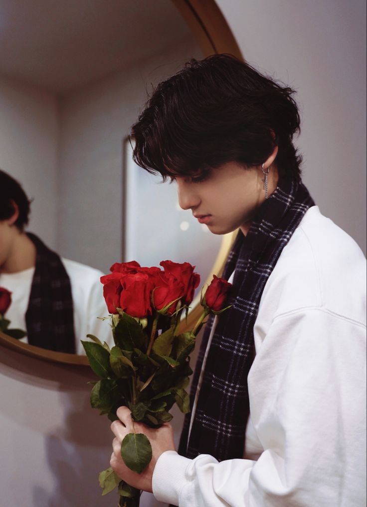 a man holding a bouquet of roses in front of a mirror