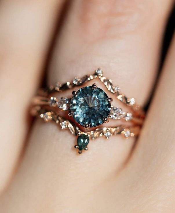 a woman's hand holding a ring with an aqua blue stone and diamond accents