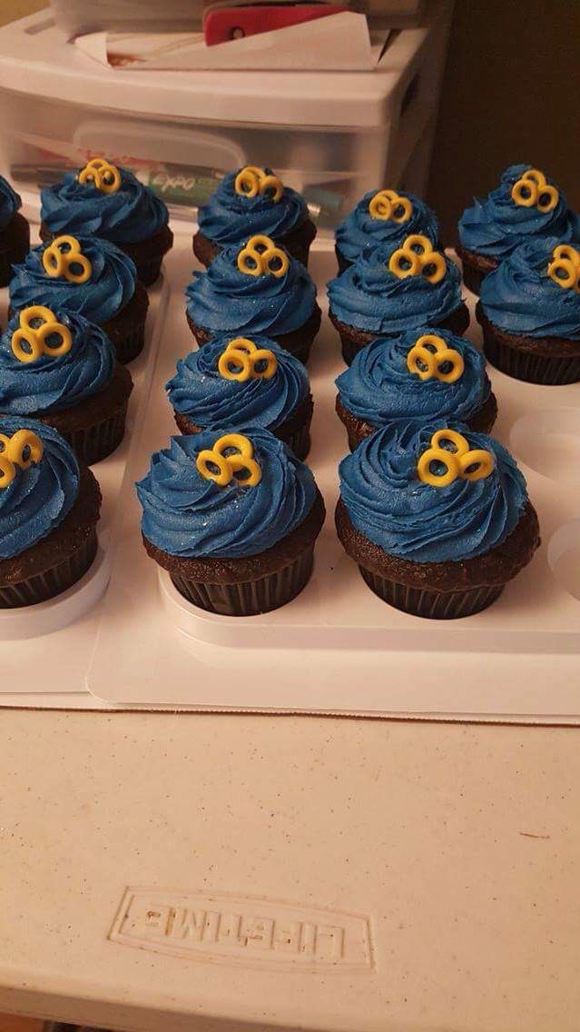 cupcakes with blue frosting and gold decorations are arranged on a white tray