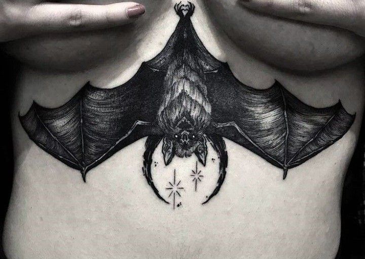 a woman's stomach with a bat tattoo on it